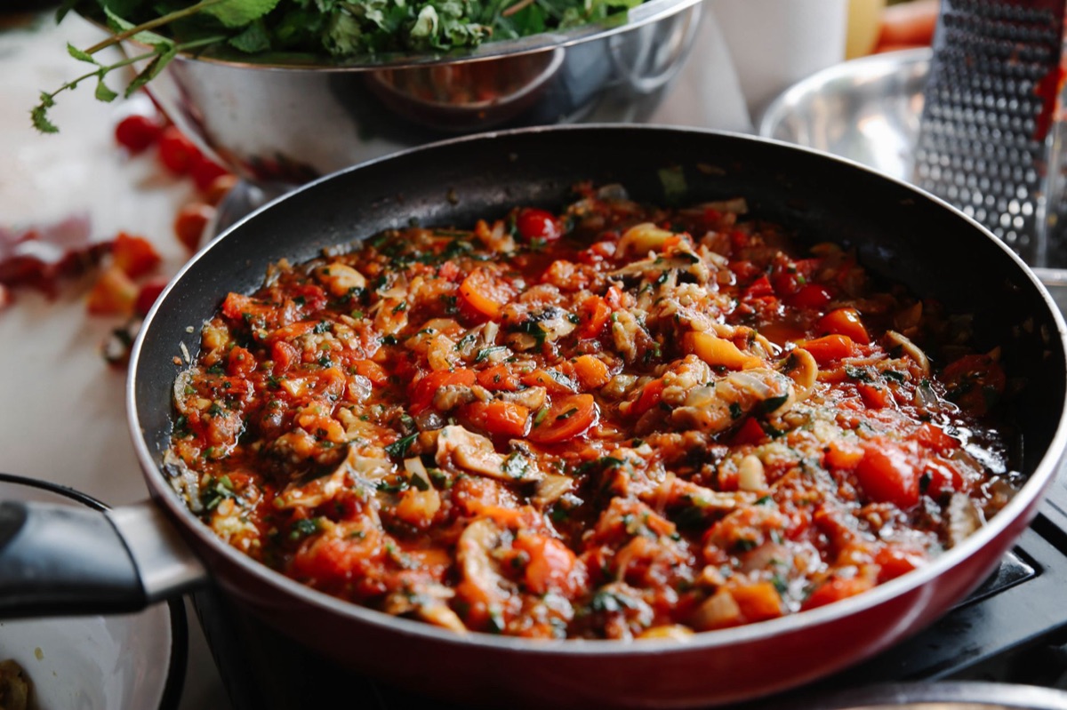 Sauce onctueuse en train d'être émulsionnée dans une poêle avec des pâtes.