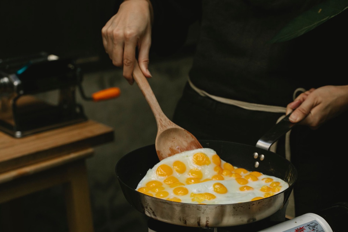 A wooden spatula lifting golden fried rice from a pan.