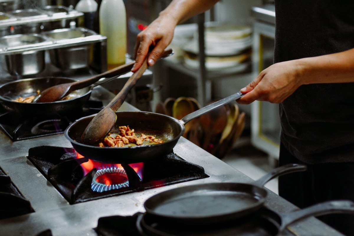 Un chef usando una espátula para saltear arroz frito en una sartén caliente.