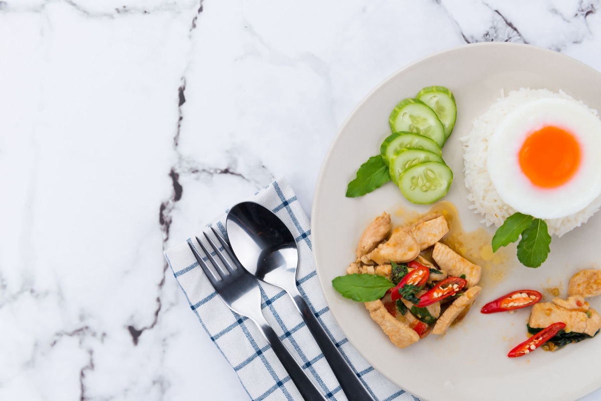 Ingredientes de arroz frito como huevo y vegetales junto a una sartén de cocina.
