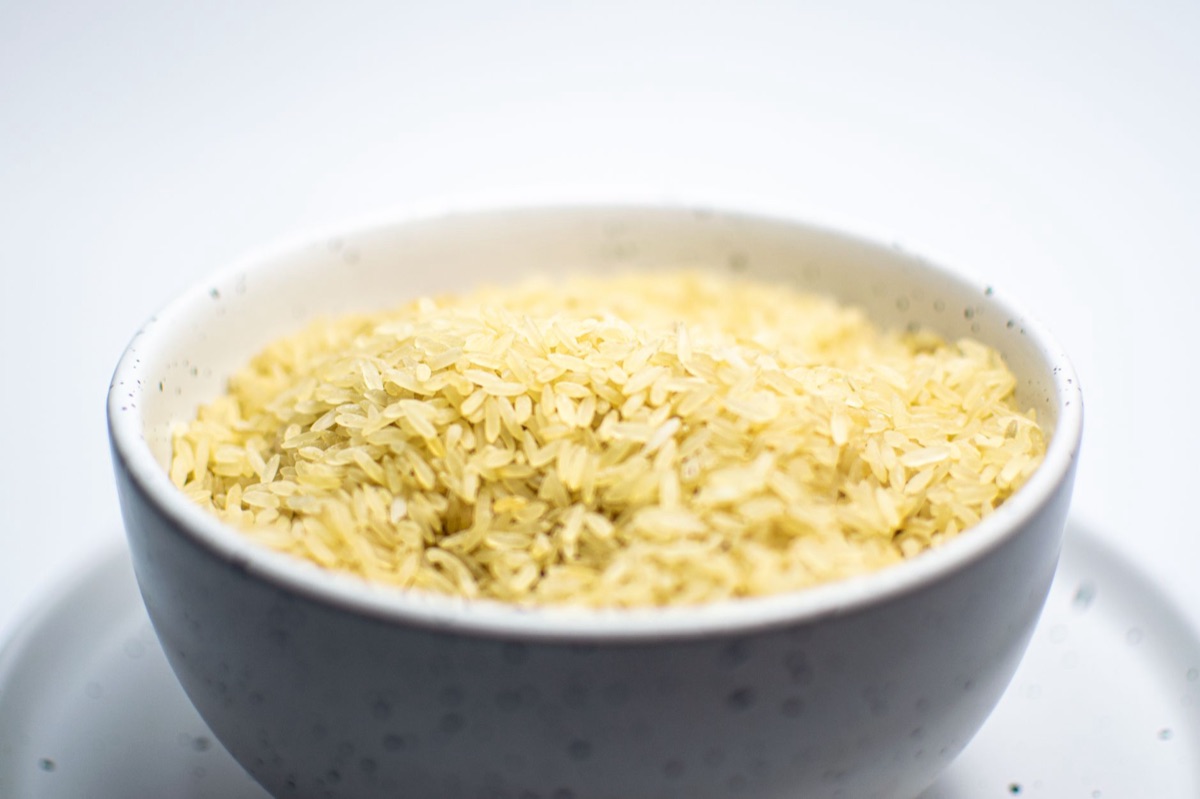 Grains de riz blanc sec dans un bol en céramique.