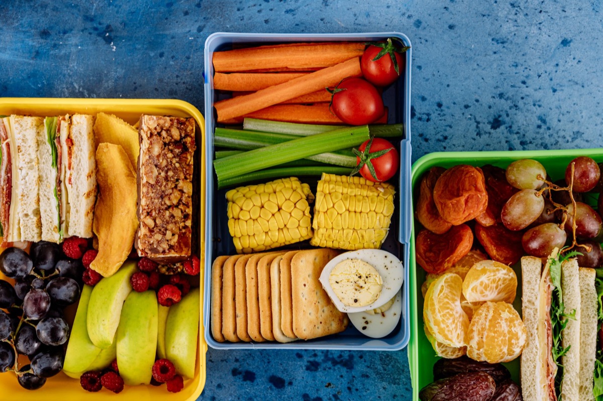 Handen die een gezonde sandwich in een lunchbox leggen