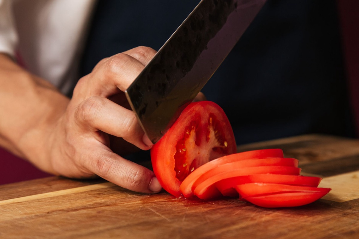 Un couteau de chef professionnel posé sur une planche à découper en bois.