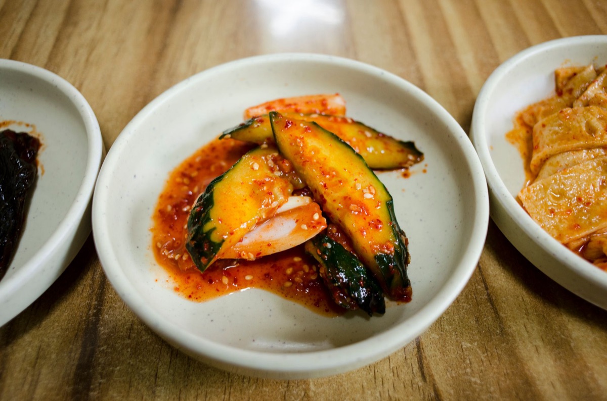 Freshly chopped kimchi and sesame oil on a wooden cutting board